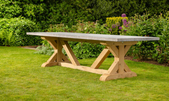 Oxenwood’s Aubrey large format outdoor dining table placed in a grassy garden