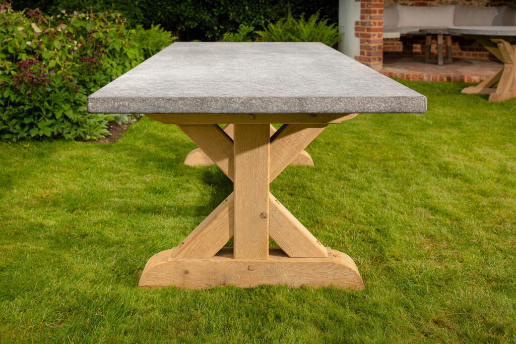Side view of the Oxenwood Aubrey Large Format Outdoor Dining Table in a grassy area
