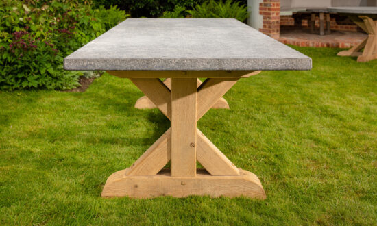 Side view of the Oxenwood Aubrey Large Format Outdoor Dining Table in a grassy area