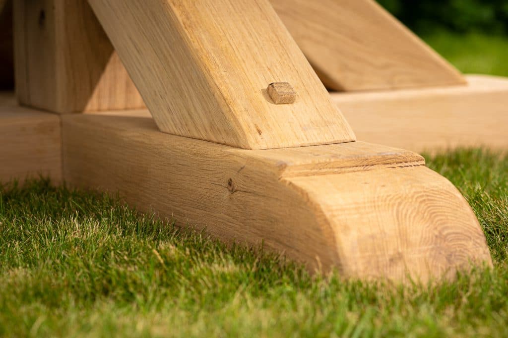 Oxenwood's large bluestone topped wooden outdoor dining table in a grassy garden area