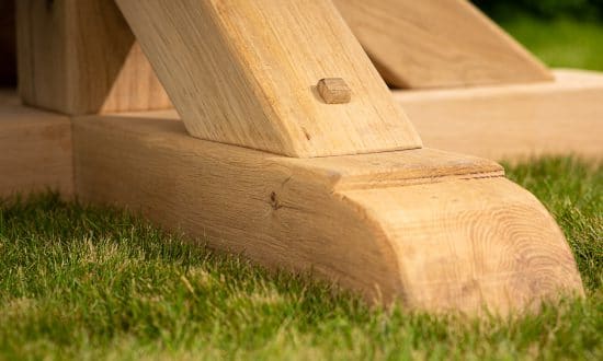 Oxenwood's large bluestone topped wooden outdoor dining table in a grassy garden area