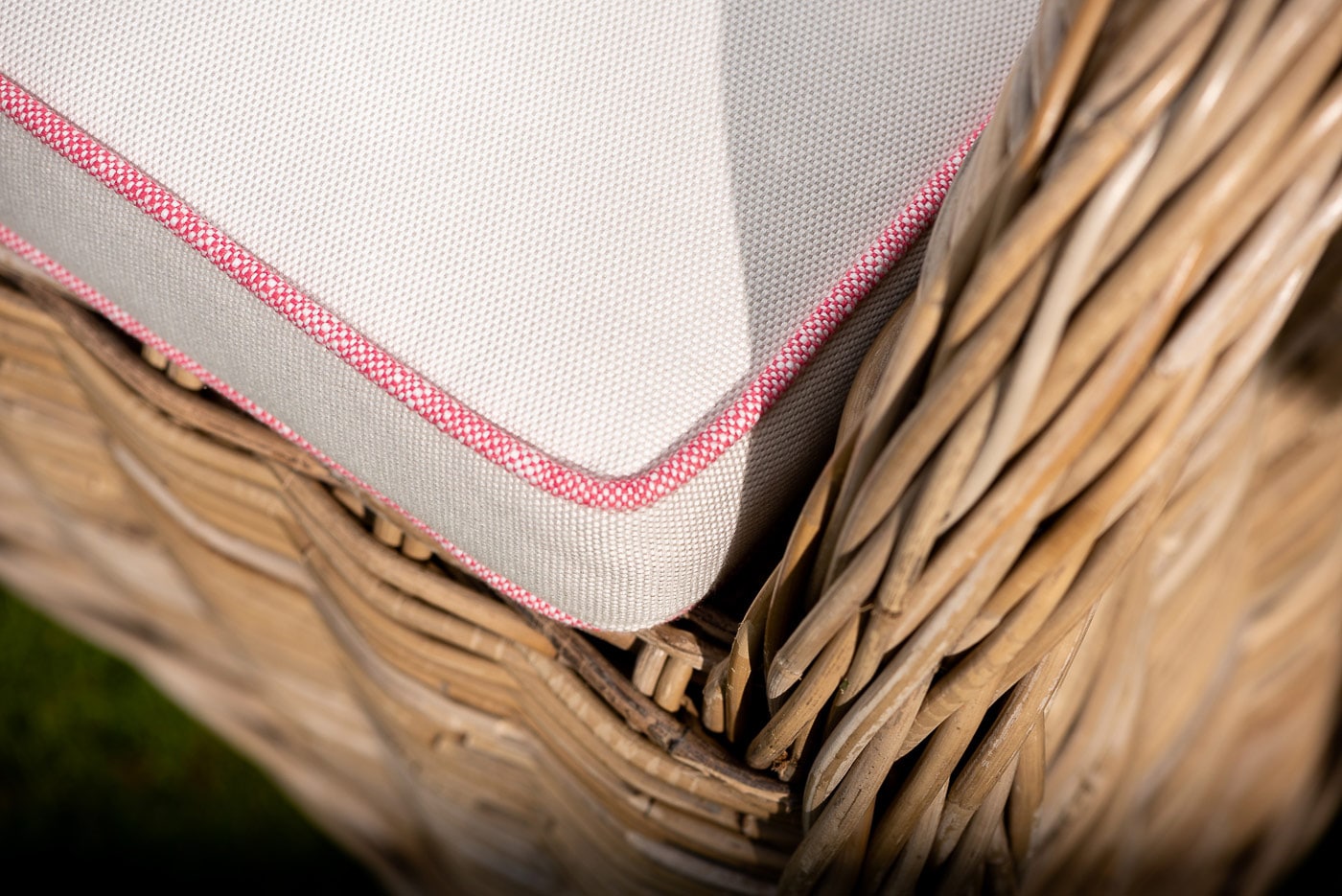 Close up of an beige and red stitched textiled cushion on a Oxenwood woven chair