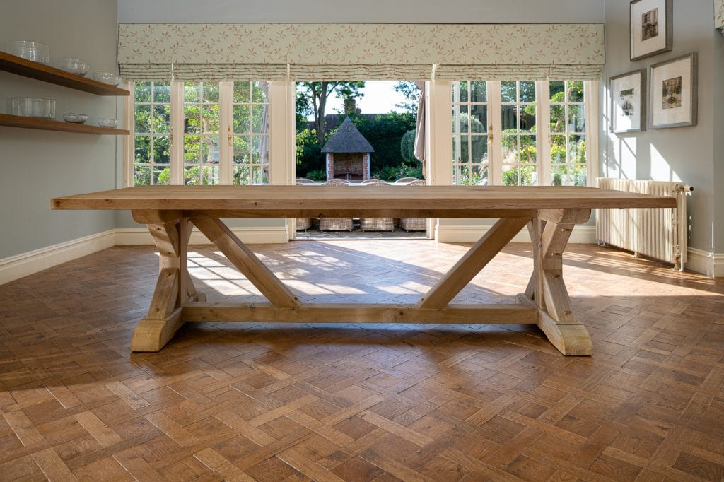 A large wooden dining table in a dining room upon a wooden parqueted flooring