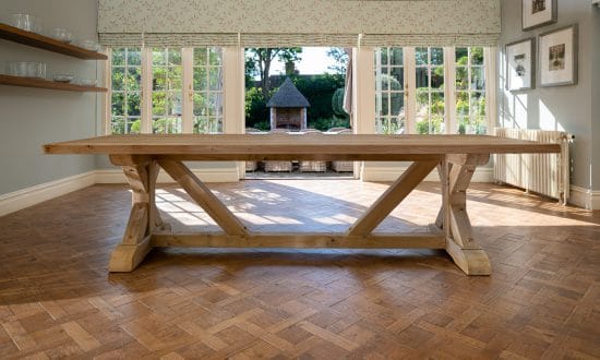 A large wooden dining table in a dining room upon a wooden parqueted flooring