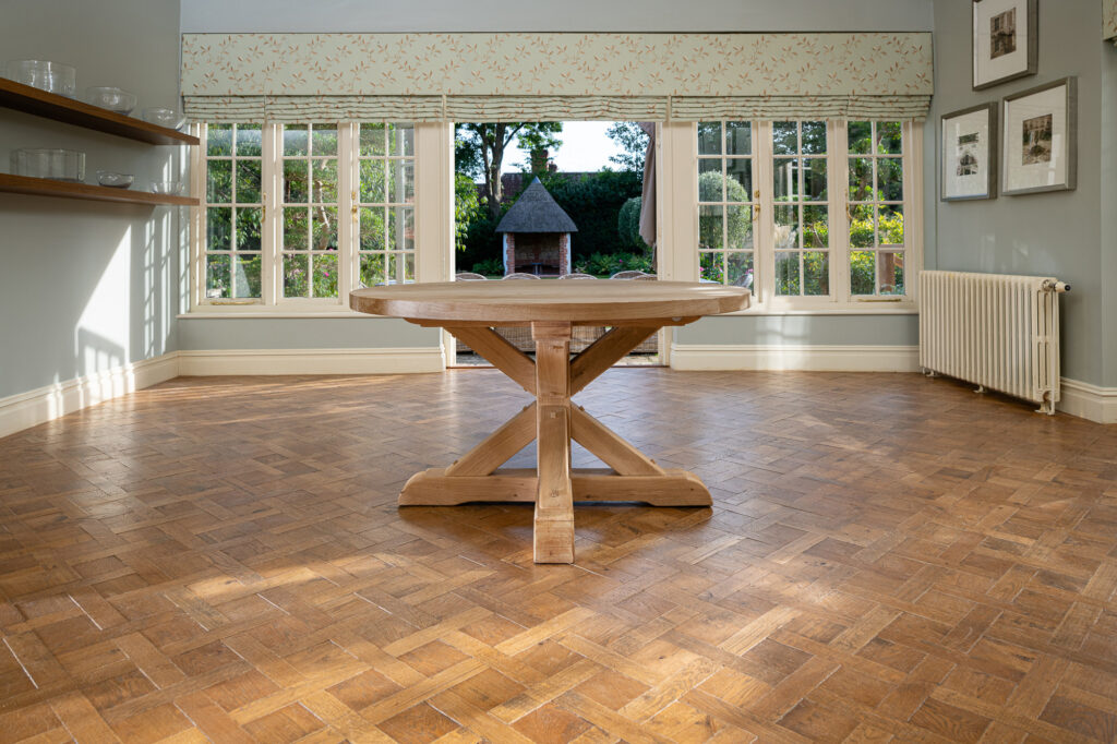 Oxenwood's wooden aubrey circular dining table shown in a parquet floored dining room