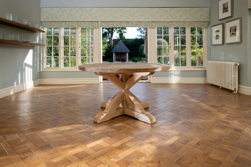 Oxenwood's wooden aubrey circular dining table shown in a parquet floored dining room