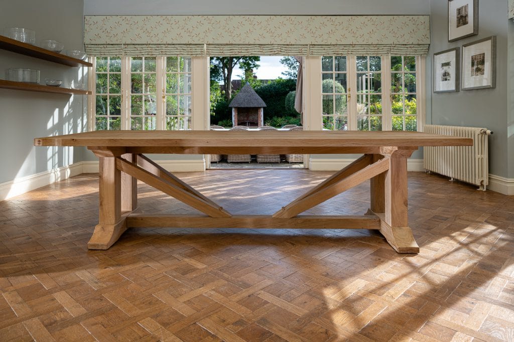 A large wooden dining table in a dining room upon a wooden parqueted flooring