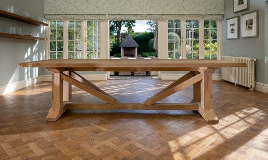 A large wooden dining table in a dining room upon a wooden parqueted flooring