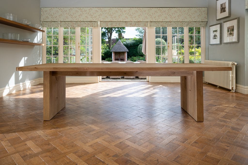A wooden dining table in a dining room upon a wooden parqueted flooring
