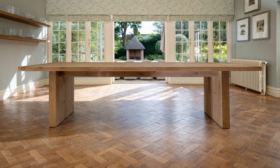 A wooden dining table in a dining room upon a wooden parqueted flooring