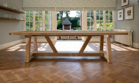 Oxenwood's wooden hollom large format dining table shown in a parquet floored dining room