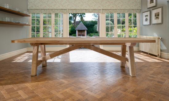 Oxenwood's wooden lucius large format dining table shown in a parquet floored dining room