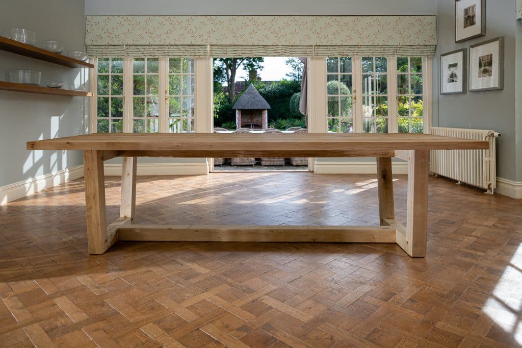 A wooden dining table in a dining room upon a wooden parqueted flooring