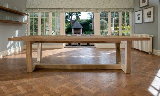 A wooden dining table in a dining room upon a wooden parqueted flooring