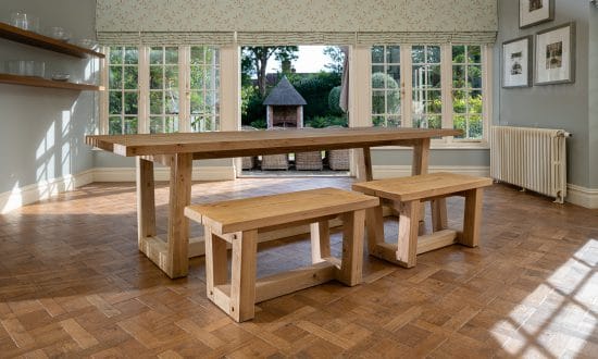 A wooden dining table and bench seating in a dining room upon a wooden parqueted flooring