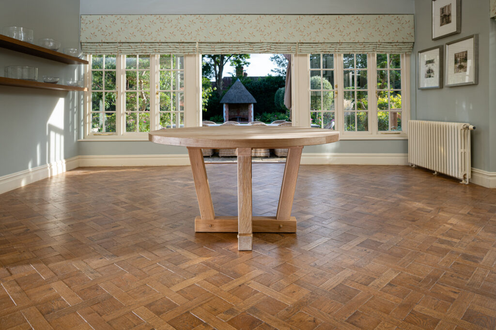 Oxenwood's wooden quintus circular dining table shown in a parquet floored dining room