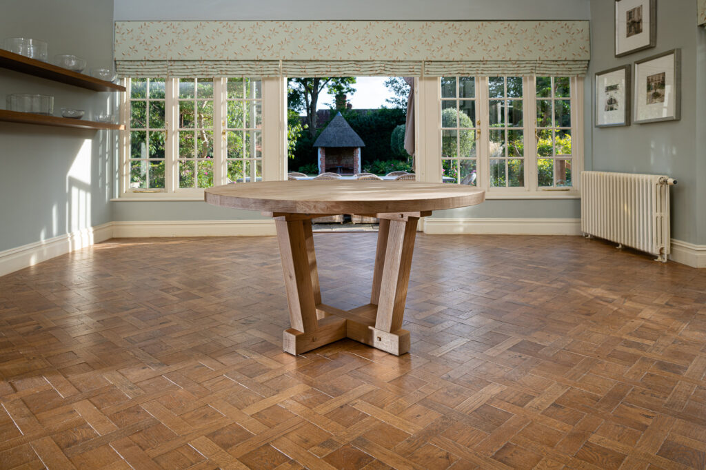 Oxenwood's wooden quintus circular dining table shown in a parquet floored dining room