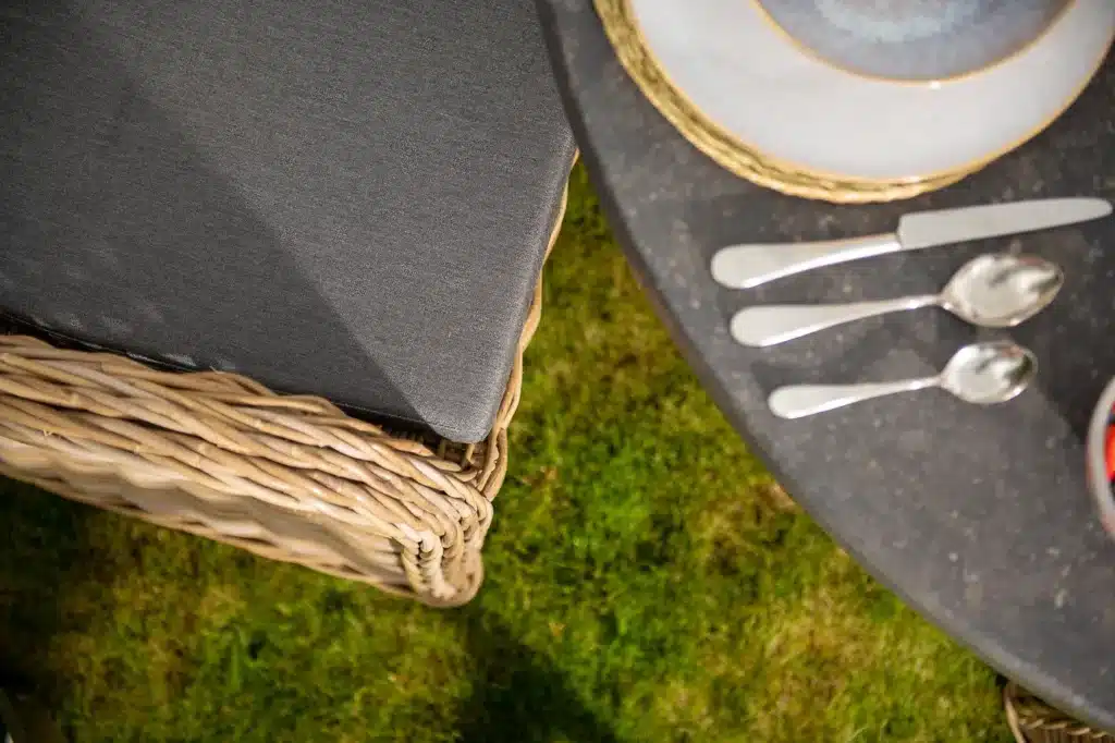 Close up of an Oxenwood branded grey textiled cushion on a woven dining chair