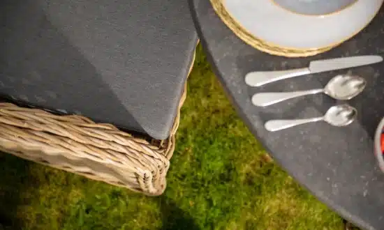 Close up of an Oxenwood branded grey textiled cushion on a woven dining chair