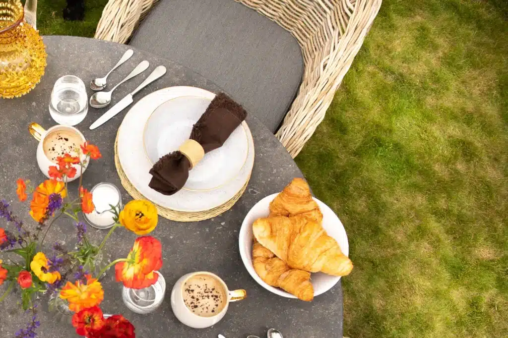 Close up of Oxenwood Quintus bluestoon table top with plates and cutlery in garden settings