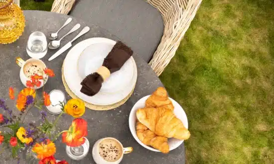 Close up of Oxenwood Quintus bluestoon table top with plates and cutlery in garden settings