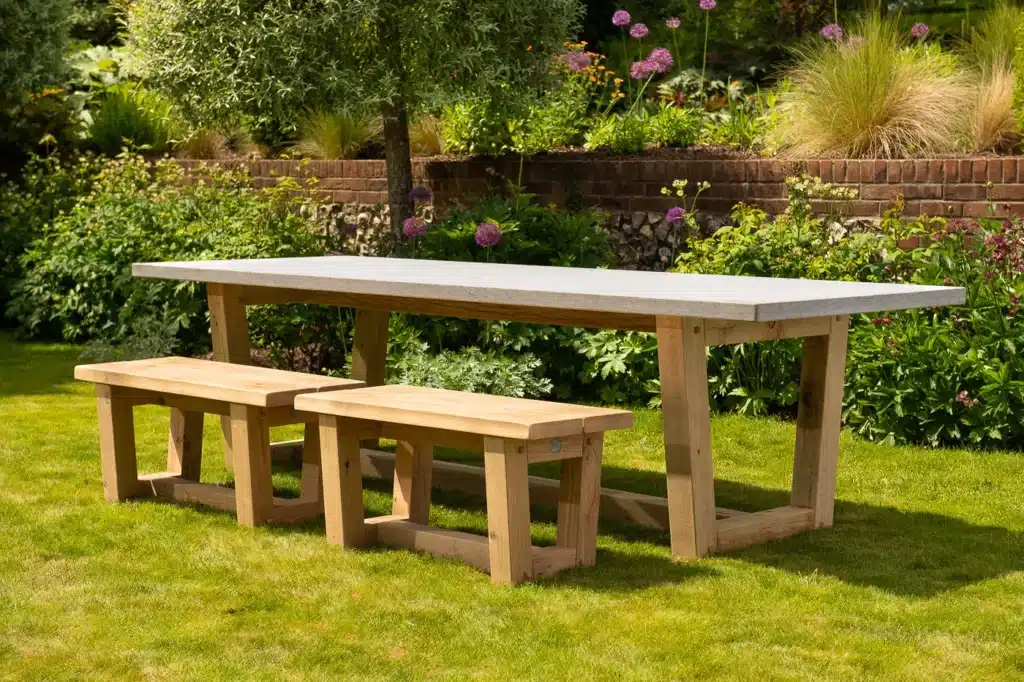 Bluestone topped outdoor dining table with benches in a grassy garden
