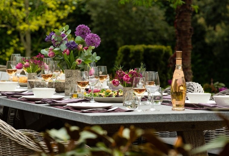 Oxenwood's Large Format Outdoor Dining Table and Woven Chairs placed in a garden area